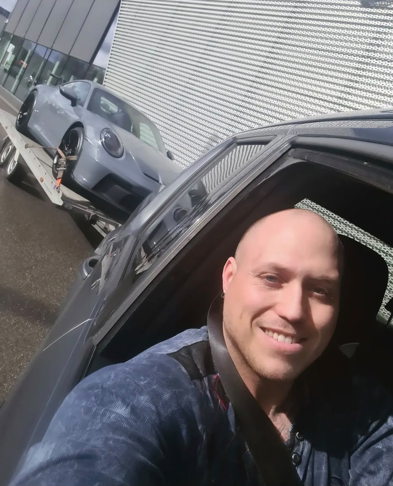 Mario Melzer, Geschäftsführer GMAPT, am Steuer – im Hintergrund ein Porsche auf dem Anhänger