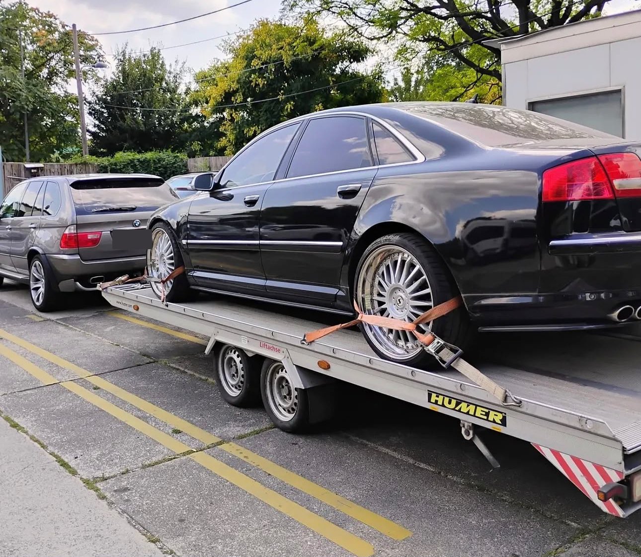 PKW mit Spanngurten gesichert auf dem Autotransport-Anhänger in einer Wiener Straße